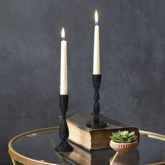 two candles sitting on top of a table next to an open book