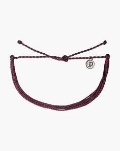 a purple cord bracelet with a silver charm on the end and a white circle in the middle