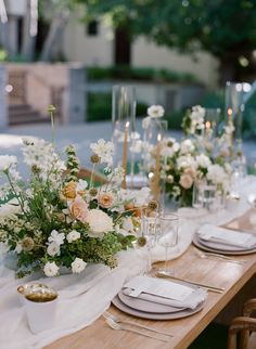 the table is set with white flowers and gold place settings for an elegant dinner party