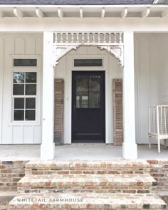 a white house with a black front door and steps leading up to the entryway