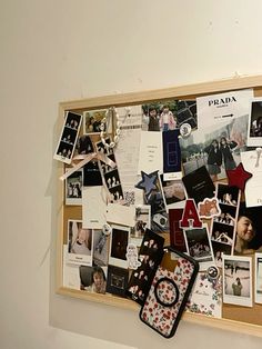 a bulletin board covered in pictures and magnets on the wall next to a cell phone