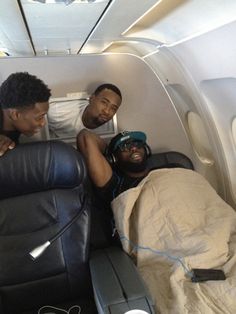 three men sitting in the back of an airplane with one man laying on his stomach