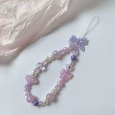 a pink and purple beaded necklace on a white surface next to a piece of fabric