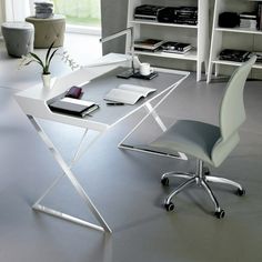 a white desk with a laptop computer on top of it next to a chair and bookshelf