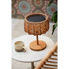 a small table with a solar panel on it and a cup next to the lamp