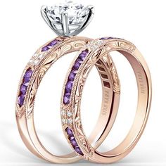 two wedding rings with pink sapphire stones on the sides and an engagement ring in the middle