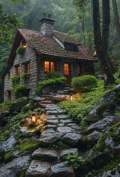 a small stone house in the woods surrounded by trees and rocks with lights on it