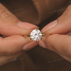 a person holding a diamond ring in their hands