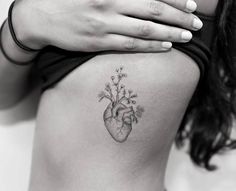 a woman's stomach with a small tattoo on the side of her body and flowers growing out of it