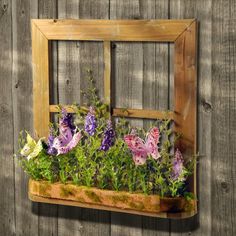 an old window is filled with flowers and greenery in front of a wooden fence