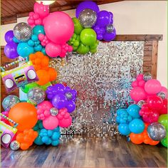 an assortment of balloons and disco balls are arranged on the floor in front of a backdrop