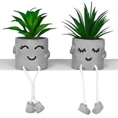 two potted plants with faces drawn on them