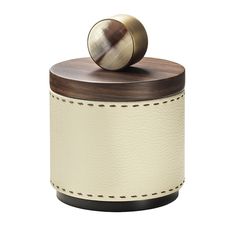 a white leather canister with a wooden lid and metal knob on the top is shown