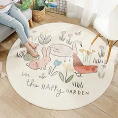 a woman sitting on the floor in front of a round rug with animals and flowers