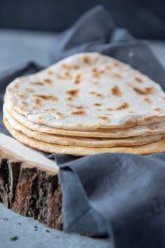 a stack of tortillas sitting on top of a piece of wood