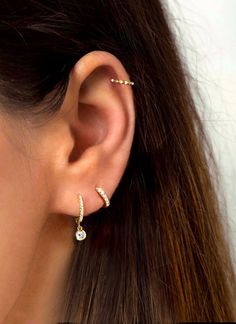 a woman's ear is shown with two small diamond earrings on top of it