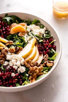 a white bowl filled with spinach, apples, walnuts and feta cheese