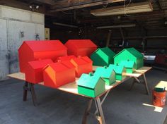 several different colored boxes sitting on top of a wooden table in a garage next to an orange bucket