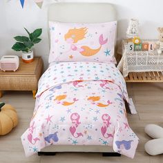 a child's bed with mermaid themed sheets and pillows