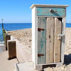 an old wooden cabinet sitting on the beach