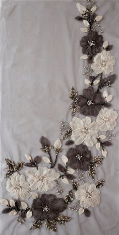 an embroidered white and grey flowered design on a gray fabric with pearls, beads and leaves