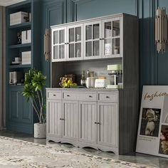 a kitchen with blue walls and white cupboards in the center, next to a potted plant