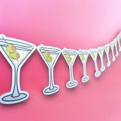 a line of glasses with drinks in them on a pink background