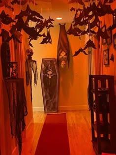 a hallway decorated for halloween with bats and decorations hanging from the ceiling, along with a red carpet