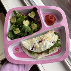 a pink tray holding a sandwich, salad and ketchup