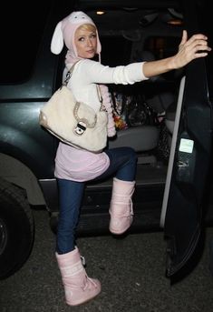 a woman in pink boots and a bunny hat leaning out the back of a truck