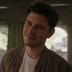 a young man smiling at the camera in a room with large windows and lots of light