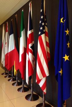 several flags are lined up against a wall in an office building, with the colors of different countries on them