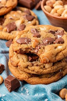 several chocolate chip cookies stacked on top of each other next to bowls of cashews