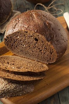 a loaf of bread sitting on top of a wooden cutting board next to sliced bread