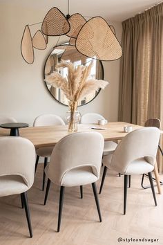 a dining room table with chairs and a round mirror