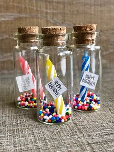 three glass bottles filled with birthday candles and sprinkles