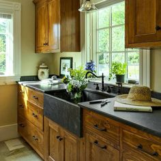 a kitchen with wooden cabinets and black counter tops, along with a large window above the sink