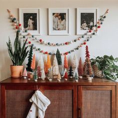 a christmas tree decorated with small trees and stockings hanging on the side of a dresser