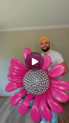 a man standing next to a giant pink flower