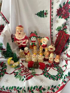 a table topped with figurines and christmas decorations on top of a white cloth