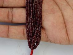 a hand holding three red beads in it's left hand and another bead on the right