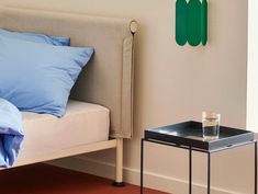 a small table with a glass on it next to a bed