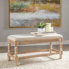 a white bench sitting on top of a rug in front of a wall with a painting above it