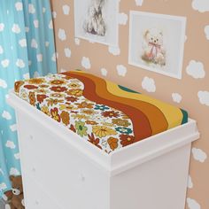 a baby's crib in the corner of a room with pictures on the wall