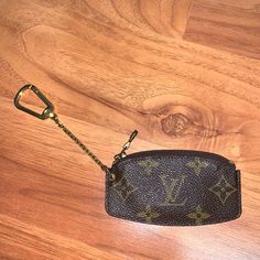 a small purse with a keychain hanging from it on a wooden floor next to a pair of scissors