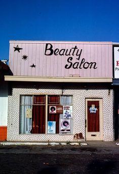 the front of a beauty salon with signs on it's windows and door frames