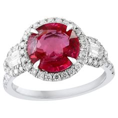 an oval shaped ruby and diamond ring with white diamonds on the band, set in 18k white gold