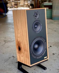 a wooden speaker sitting on top of a black stand