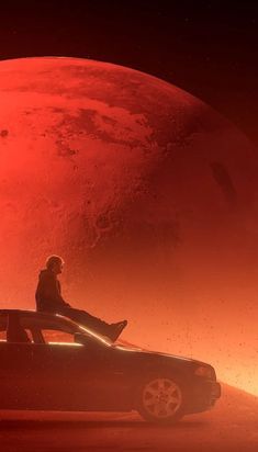 a man sitting on top of a car in front of a red planet