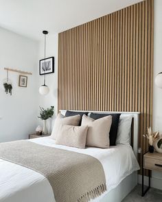 a bed with pillows and blankets on it in front of a wooden paneled wall